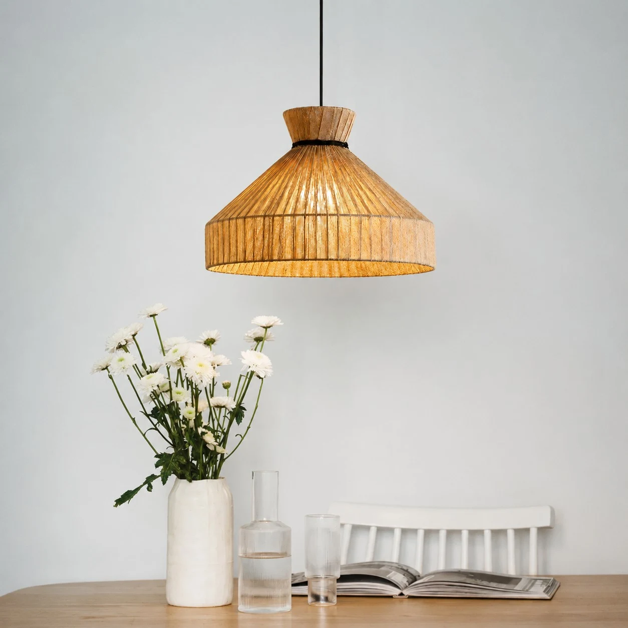 Fabric cone pendant light above a dining table with flowers