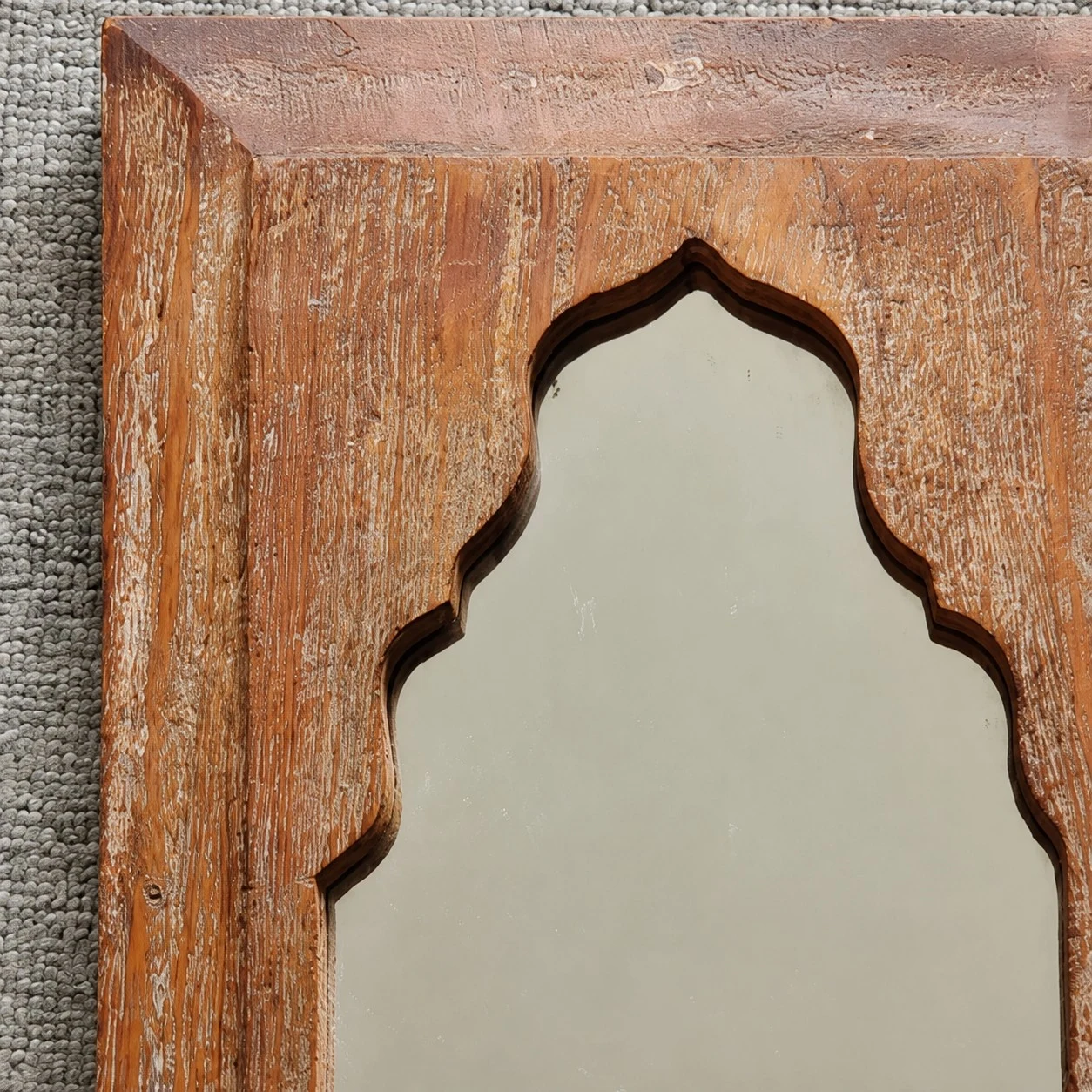 Detailweergave van het gebeeldhouwde boogdetail op de houten spiegelrand.