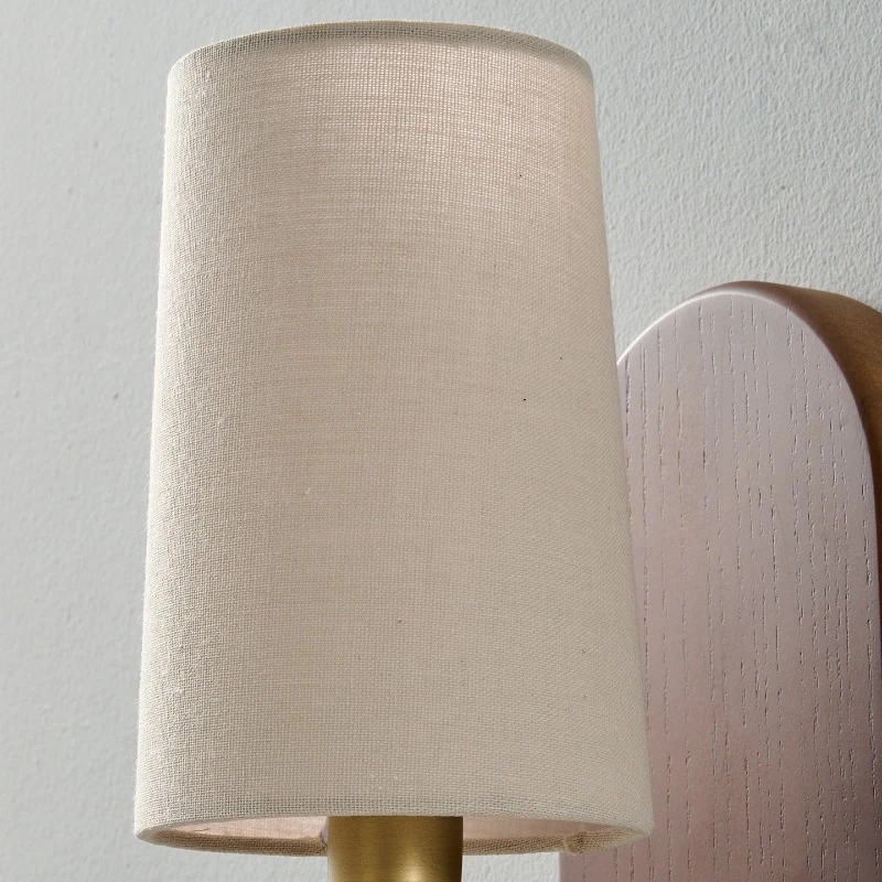 Il paralume in tessuto intrecciato diffonde la luce della lampadina creando una delicata luminescenza ambientale, rendendo l'applique adatta da posizionare accanto a un letto, un divano, una consolle o lungo una parete stretta di un corridoio.