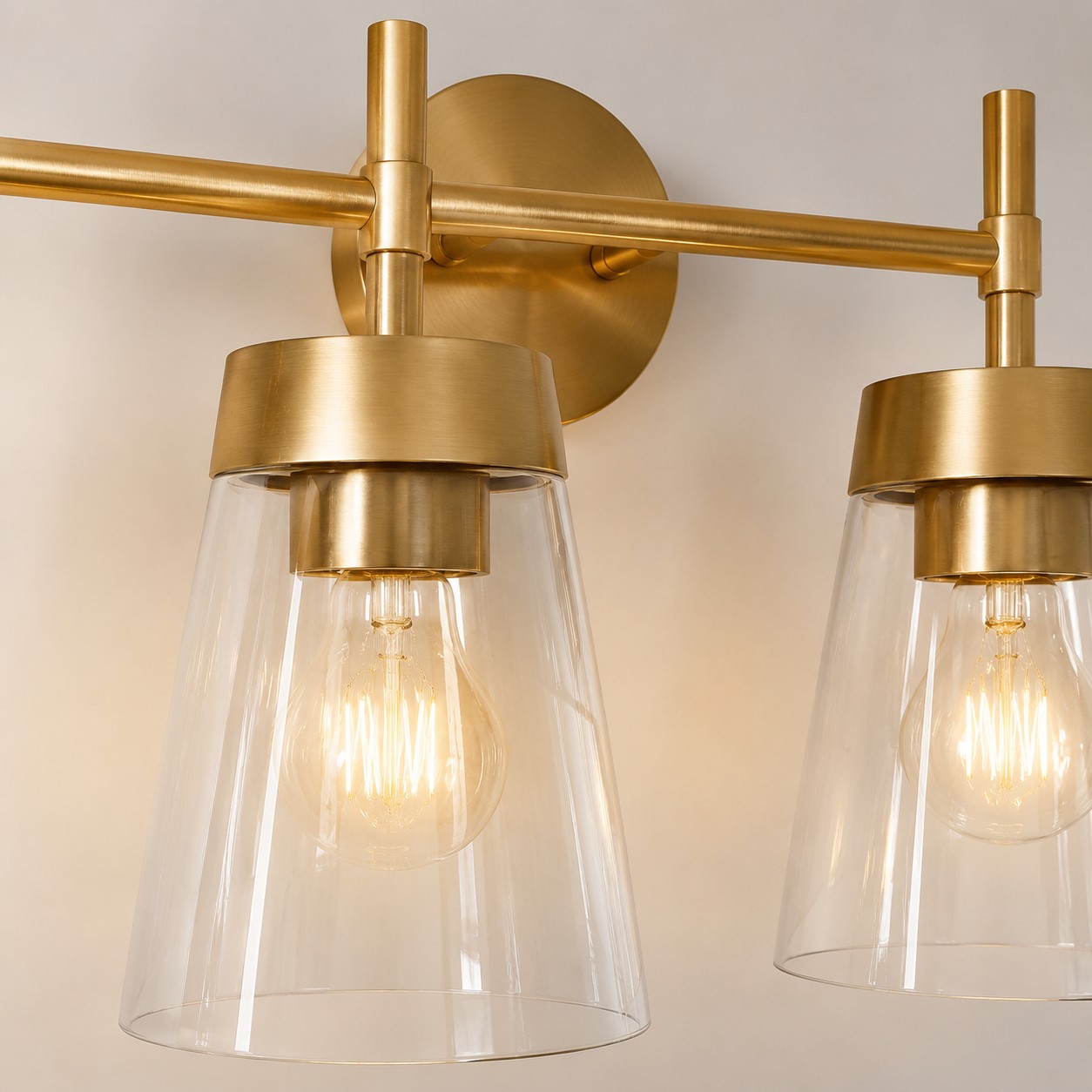 Lampada da bagno in ottone spazzolato con paralume in vetro trasparente.