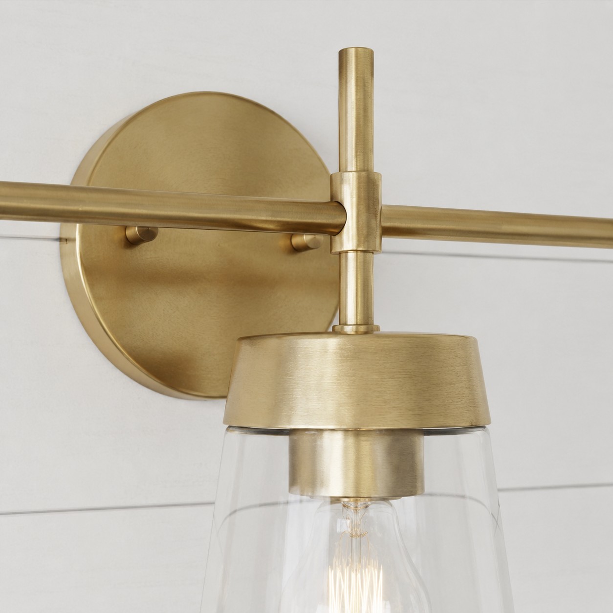 Placca di supporto e dettaglio del braccio per applique da bagno in ottone spazzolato.